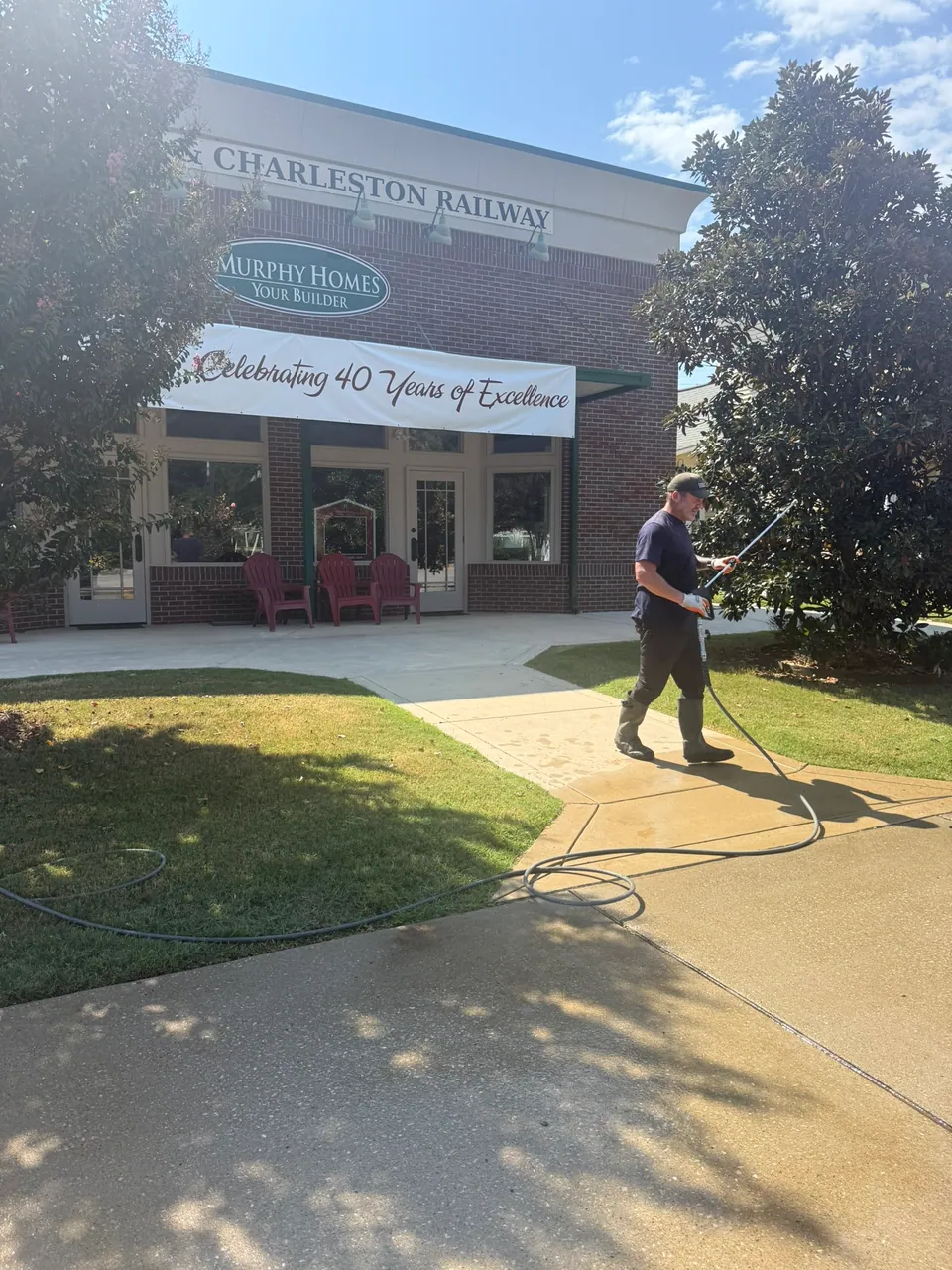 Operator pressure washing a walkway beside a commercial property