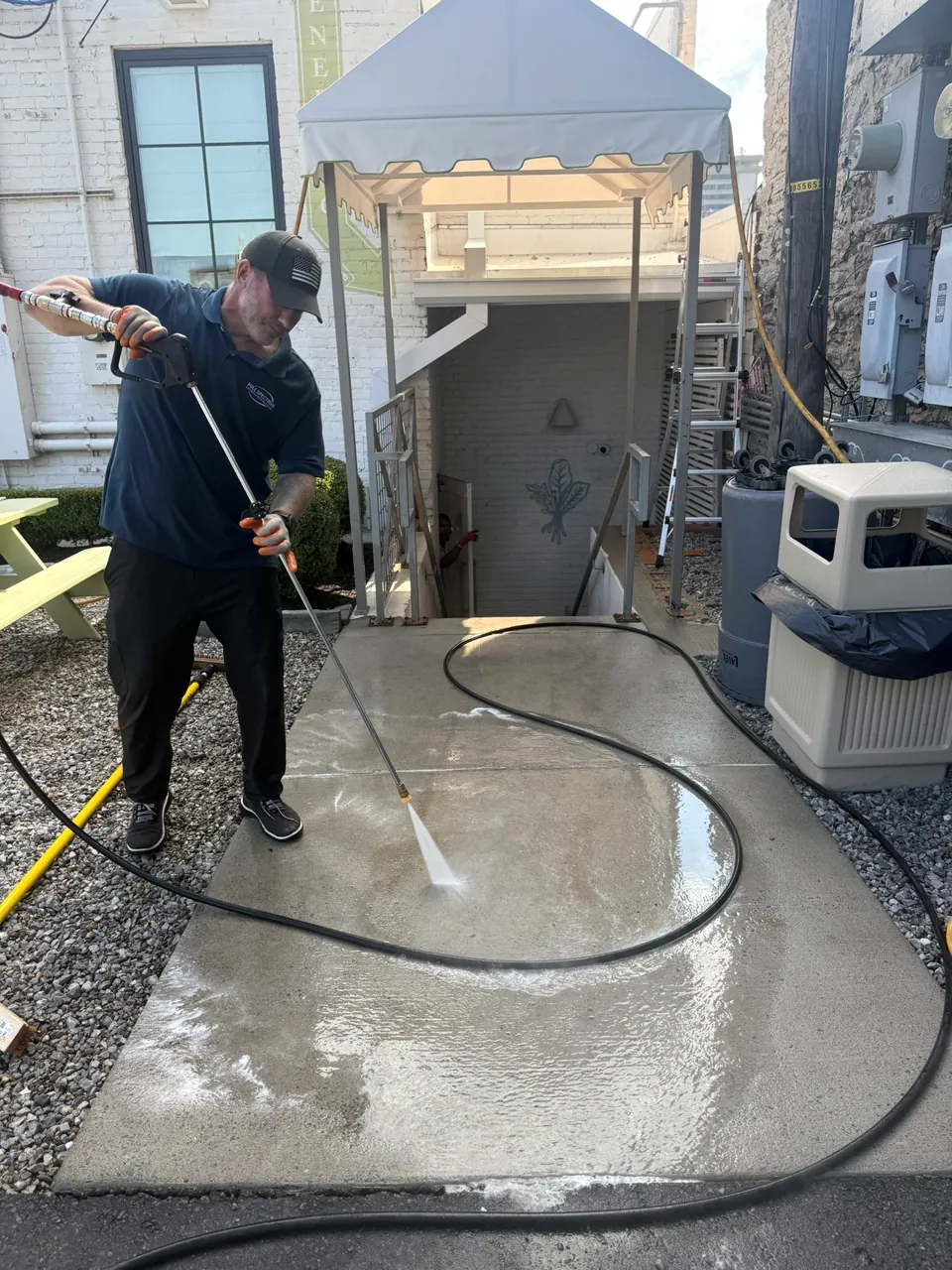 Operator washing the concrete surface of an outdoor courtyard